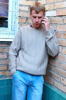 Young stylish man talk on mobile phone near brick wall.