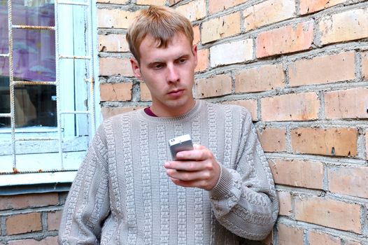 Young stylish man talk on mobile phone near brick wall.