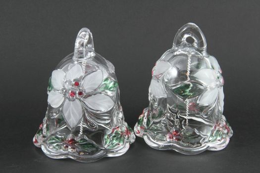 A pair of glass Christmas bells on a grey background.