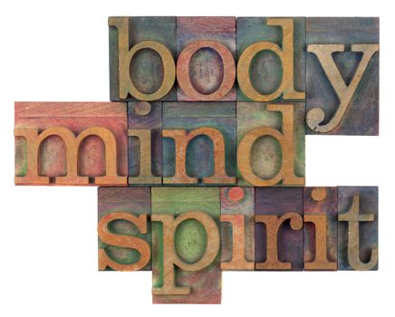 body, mind and spirit in vintage wooden letterpress types, stained by ink in different colors, isolated on white