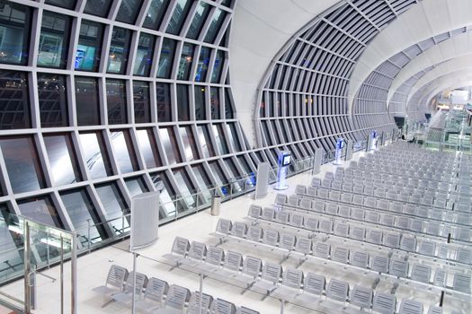 Modern airport lobby at night with empty chairs.