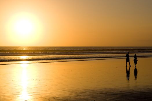 Couple walking on the beach at sunset.