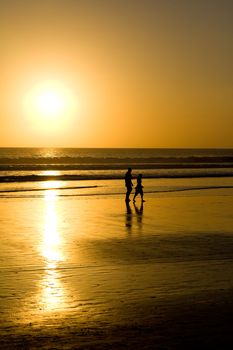 Couple walking on the beach at sunset.