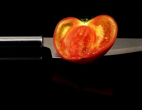 tomato sliced with knife on black background