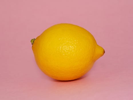 whole fresh lemon over pink background