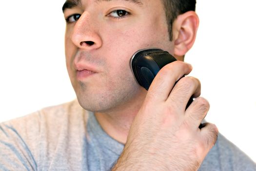 A closeup of a young man shaving his beard off with an electric shaver.