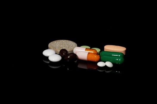 assorted medicine pills on black background with reflections
