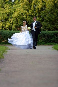 Groom gently embraces the bride in park