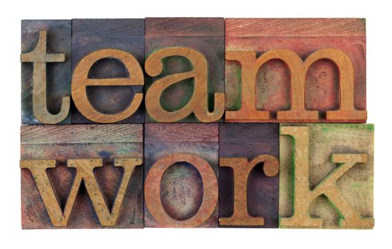 the word teamwork in vintage wooden letterpress type, stained by colorful inks, isolated on white