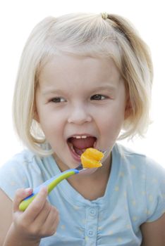 Young child eating tangerine on a fork.  Isolated on a white background