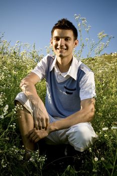 Boy among a field of daisies, with a clear blue sky as background and a peaceful atmosphere.