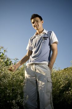 Boy among a field of daisies, with a clear blue sky as background and a peaceful atmosphere.