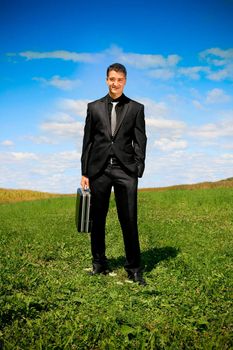 Young businessman outdoor holding a suitcase.