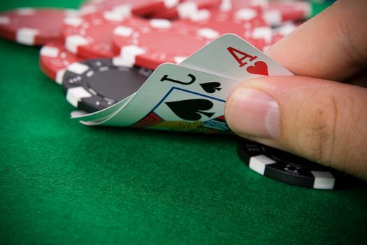 Ace of hearts and black jack with red poker chips in the background.