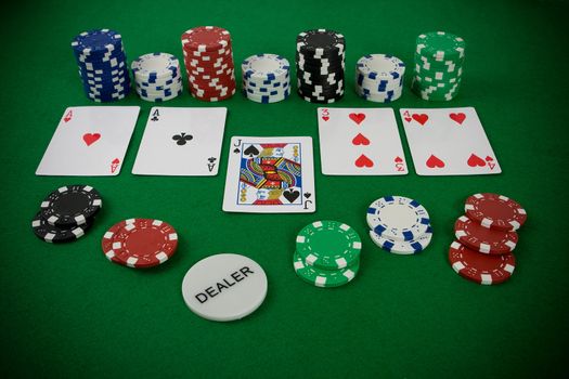 Poker set, cards and poker chips on green table.