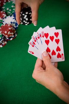 Cards with poker arrangement and female hand betting in the background.