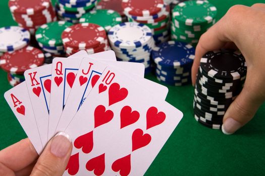 Cards with poker arrangement and female hand betting in the background.