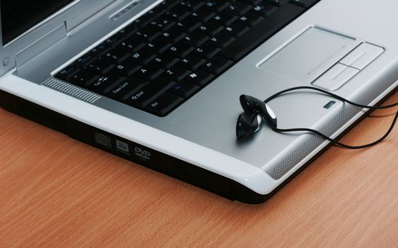 Laptop on desk with headphones on it.