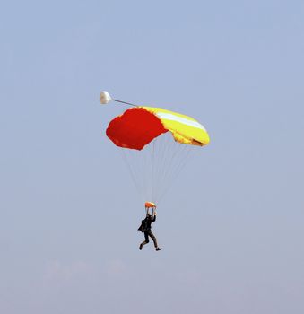 Man pending from a red and yellow parachute