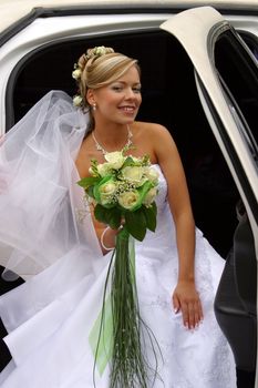 The beautiful bride with a bouquet in the automobile