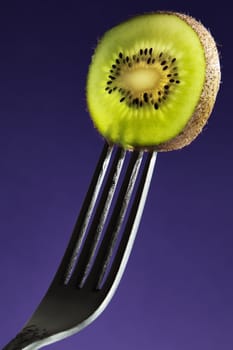 Kiwi fruit on a fork with sidelighting to highlight the fruit