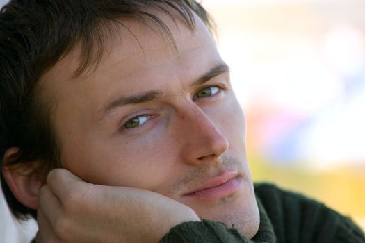 Portrait of the young man in a green sweater on an abstract background