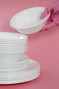 white bowls and plates stacked, pink background