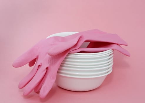 pink gloves on pile of stacked white bowl.