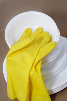 yellow gloves on pile of stacked white bowl.