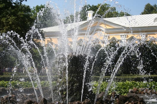 fountain in the park with yellow building
