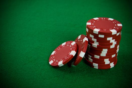 Stack of red poker chips on a green poker table background.