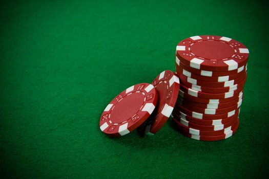 Stack of red poker chips on a green poker table background.