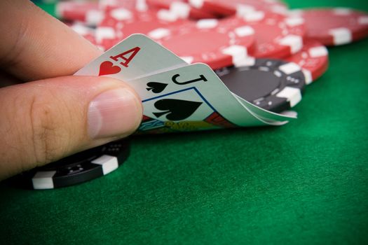 Ace of hearts and black jack with red poker chips in the background.