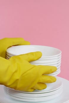 hands with yellow gloves holding white dishes