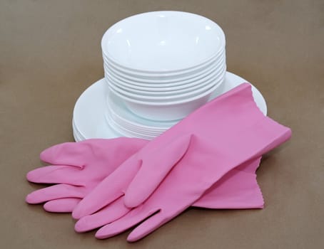 pink gloves and white dishes stacked, brown background