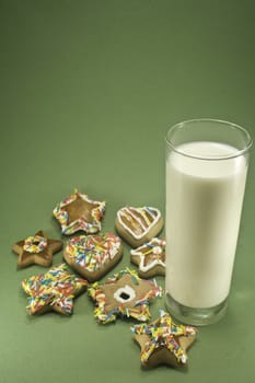 Christmas cookies and a glass of milk isolated against green paper