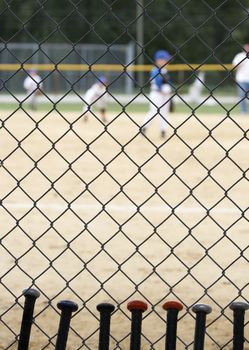 baseball bats learning against dugout fence as game is played