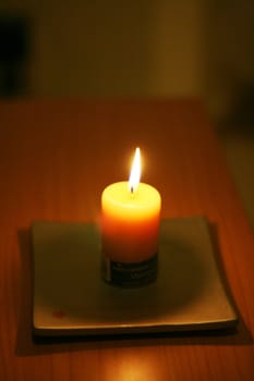 A glowing candle on a square plate
