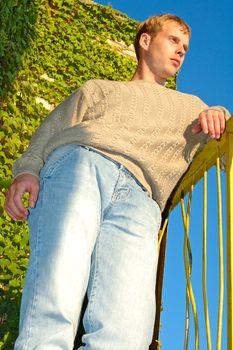 Young stylish blonde man stay near overgrown with vine wall.