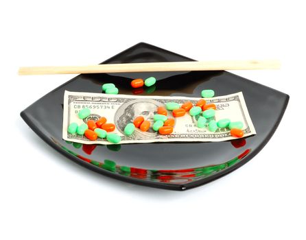 expensive chemical diet - colored pills on black asian plate, 100 dollar note, and chopsticks