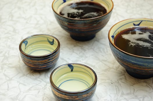 four asian bowls on the table - sake and soup with soy