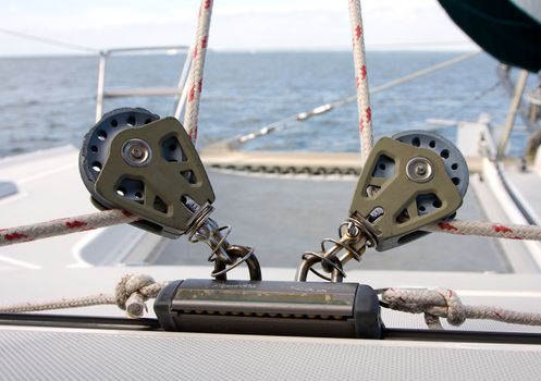 Two reels that are used to adjust the front sails on a Catamaran with a view of the horizon and trampoline