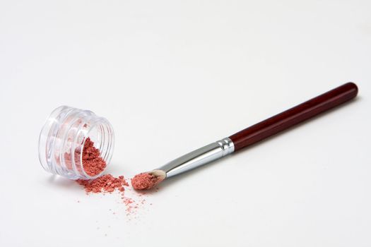 Translucent pink powder in a jar and on brush, isolated