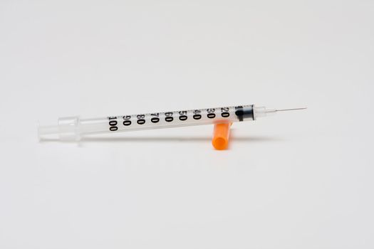 Insulin syringe with orange cap and needle, isolated