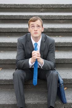 A worried business man sitting on some stairs