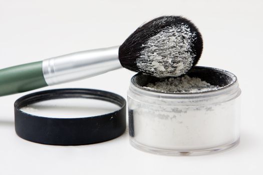 Translucent white powder in a jar and on brush, isolated