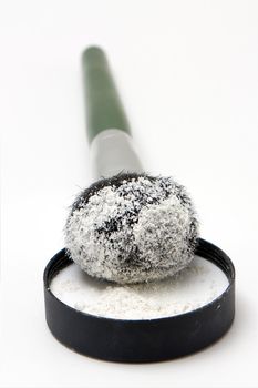 Translucent white powder in a jar and on brush, isolated