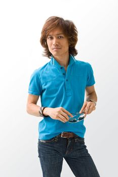 Happy Asian guy in blue t-shirt holding sunglasses, isolated