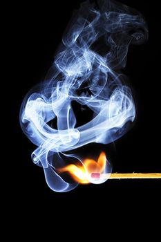 one match is igniting in front of black background with blue smoke