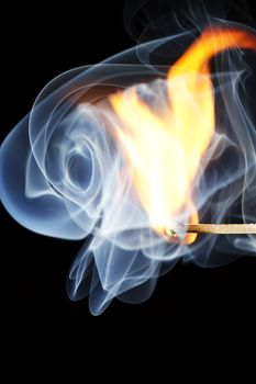 one match is igniting in front of black background with blue smoke